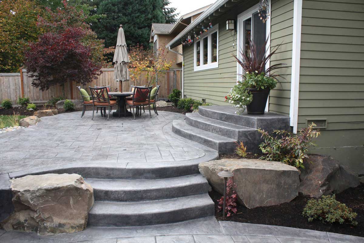Stamped concrete patio with curved steps and boulder accents
